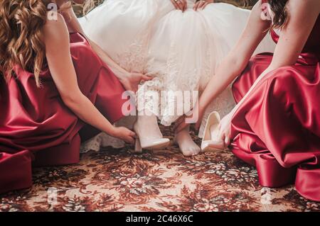 Brautjungfern helfen Braut, auf elegante Schuhe setzen Stockfoto