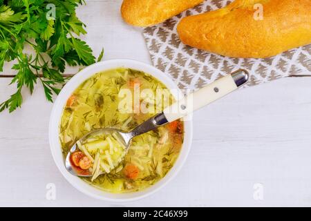 Löffel voll Hühnernudelsuppe in Schüssel mit Brot. Stockfoto