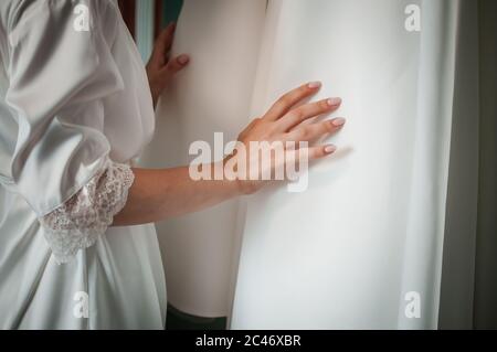 Braut legt Hand auf Hochzeitskleid Stockfoto