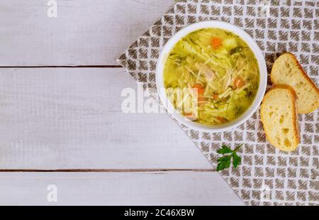 Hühnernudelsuppe in weißem Teller mit Petersilie und Brot. Draufsicht. Stockfoto
