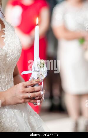 Braut hält weiße Kerze in der Hand Stockfoto