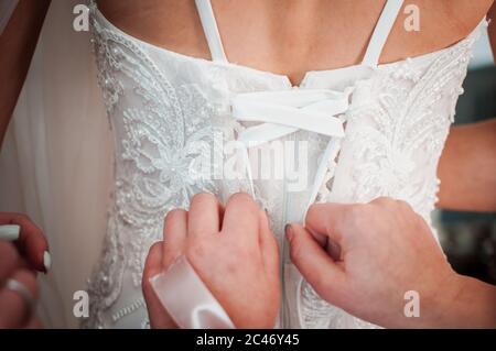 Brautjungfern helfen Braut Hochzeitskleid zu tragen Stockfoto