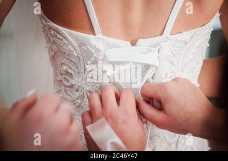 Brautjungfern helfen Braut Hochzeitskleid zu tragen Stockfoto