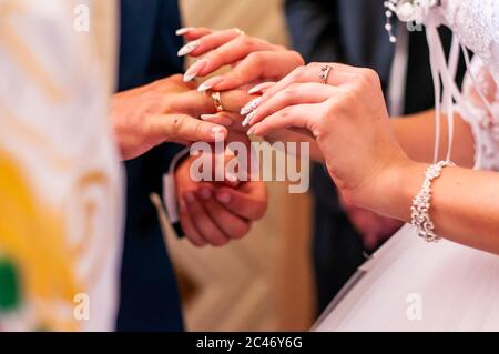 Braut trägt goldenen Ehering auf dem Bräutigam Finger Stockfoto