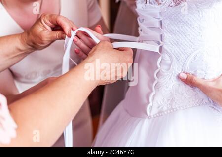 Brautjungfern schnüren das Brautkleid Stockfoto