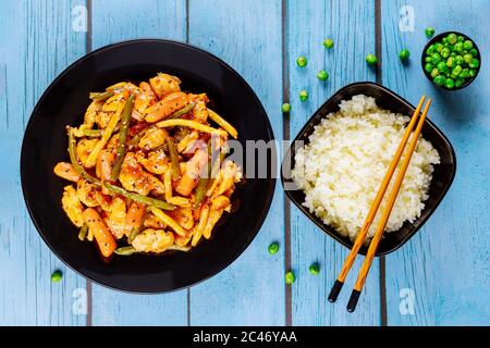 Hühnerteriyaki, Gemüse mit Reis in schwarzer Platte mit Essstäbchen. Stockfoto