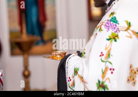 Priester hält Goldbecher mit Wein in den Händen Stockfoto