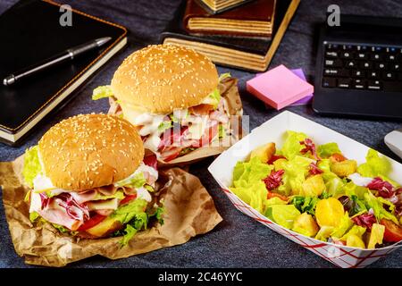 Schnellimbiss, Sandwich und Salat. Konzept „Work from Home“. Stockfoto