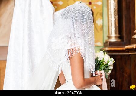 Braut im Schleier bleibt in der Kirche Stockfoto