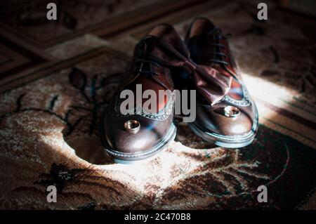 Braune Herrenschuhe Fliege und Paar goldene Eheringe Stockfoto