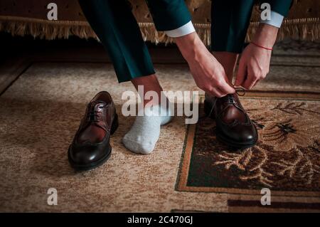 Der weiße Mann legt schwarze Schuhe auf die Beine Stockfoto