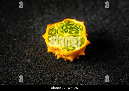 Kiwano Obst in der Mitte auf dunkelgrauem Hintergrund geschnitten Stockfoto