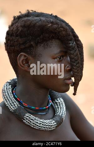 KAMANJAB, NAMIBIA - 1. FEB 2016: Junges, nicht identifiziertes Himba-Mädchen mit der typischen Halskette und Doppelzopf-Frisur des vorJugendlichen Stockfoto