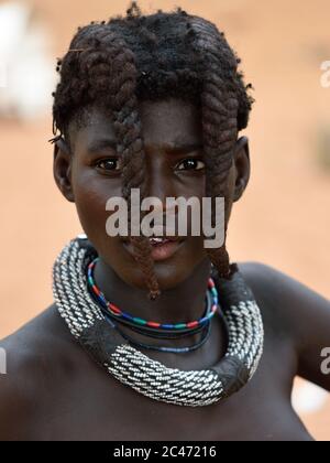 KAMANJAB, NAMIBIA - 1. FEB 2016: Junges, nicht identifiziertes Himba-Mädchen mit der typischen Halskette und Doppelzopf-Frisur des vorJugendlichen Stockfoto