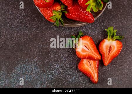 Frisch geschnittene reife Erdbeeren auf einem Teller auf grauem Hintergrund. Stockfoto