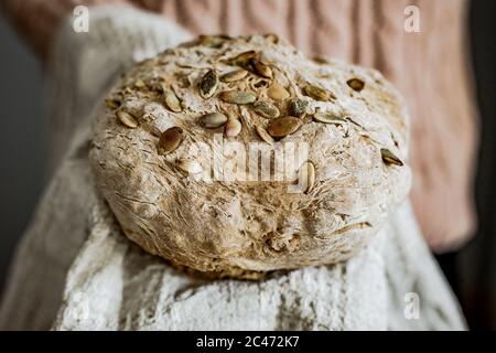 Halten Sie ein Laib frisches hausgemachtes Vollkornbrot auf einem beigen Handtuch, horizontal rustikalen Stil Foto Stockfoto