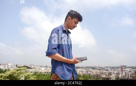 Mann Hände halten schwarzen Smartphone-Gerät, scrollt den Bildschirm . Stadt Hintergrund. Stockfoto