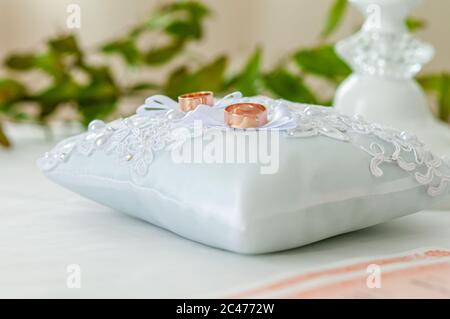 Ein Paar goldene Eheringe auf dem weißen Kissen Stockfoto