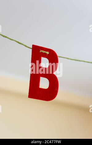 Nahaufnahme eines roten B-Buchstabens, der an A hängt Kabel mit unscharfem Hintergrund Stockfoto