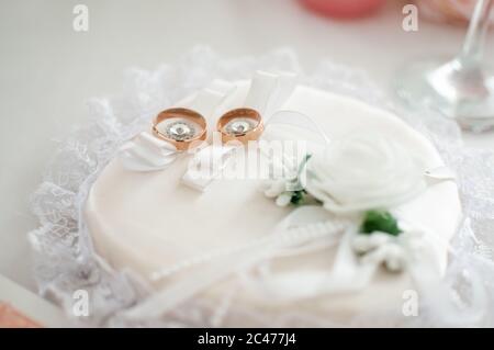 Ein Paar goldene Eheringe auf dem weißen Kissen Stockfoto