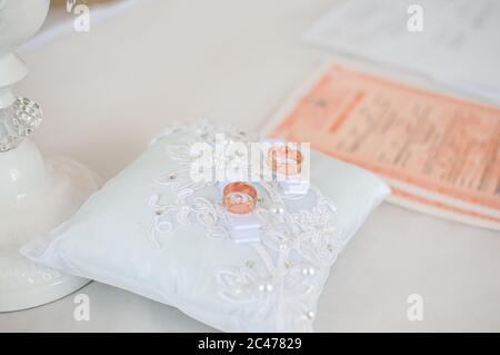 Ein Paar goldene Eheringe auf dem weißen Kissen Stockfoto
