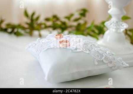 Ein Paar goldene Eheringe auf dem weißen Kissen Stockfoto