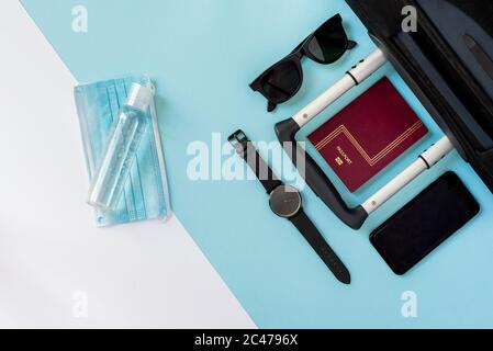 Horizontales Farbbild mit einer Ansicht von oben auf einem Reisenden Zubehör auf einem Sommerurlaub 2020 mit dem Coronavirus auf einem blau-weißen Hintergrund. Stockfoto