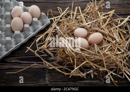 Hühnereier weiß und braun. Eier in Stroh, auf einem hölzernen Hintergrund Stockfoto