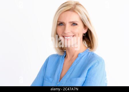 Porträtaufnahme einer schönen Seniorin, die die Kamera betrachtet und lächelt, während sie auf einem isolierten weißen Hintergrund steht. Stockfoto