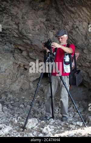 Naturfotograf mit Digitalkamera. Er ist in einer Grotte. Stockfoto