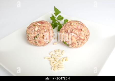 Nahaufnahme von Fleischbällchen mit Grüns und Gewürzen in einem Weiße Platte Stockfoto