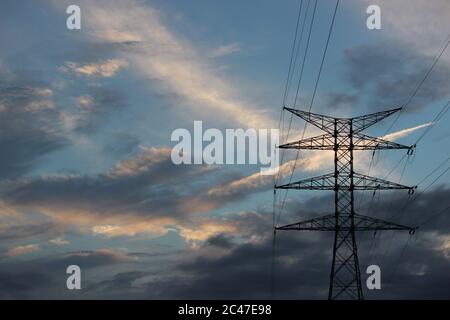 Elektrischer Turm, der mit Kabeln unter dem wolkigen Himmel verbunden ist Stockfoto