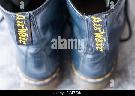 Ein Paar schwarze Dr. Martens Lederstiefel mit schwarzen Schnürsenkeln auf grauem Hintergrund. Stockfoto