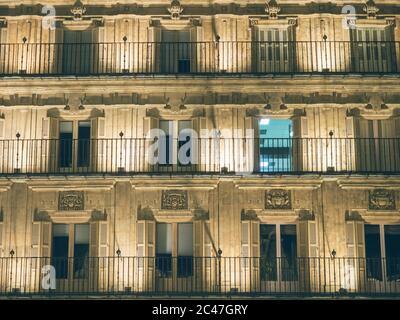 Altes Gebäude mit Fenstern und wunderschönen Schnitzereien bei Nacht Stockfoto