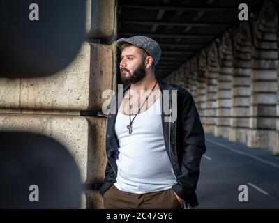 Junger hübscher französischer bärtiger Mann, der in Paris, Frankreich, unter einer Brücke mit natürlichem Licht nach draußen gebracht wurde Stockfoto