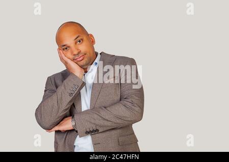 Schöner afroamerikanischer junger Kerl, der seinen Kopf mit der Hand hält und nach einem langen und harten Arbeitstag müde ist. Stockfoto