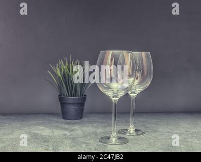 Zwei leere Weingläser auf Grey Table mit Grüntopf Closeup Date Konzept Stockfoto