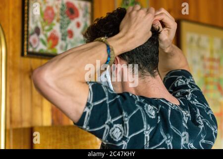 Junge männliche Anziehen Deluxe Stoff Maske Seite muskulösen jungen Mann in dunkel gemusterten Hemd auf hellem Holz Hintergrund Stockfoto