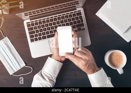 Modell bis leeren Bildschirm des modernen Smartphones in männlichen Händen über Laptop-Computer, Geschäftsmann mit Handy, Draufsicht Stockfoto