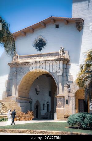 Beachten Sie die spanische Inschrift über dem Eingang des Santa Barbara County Courthouse durch den Säulenbogen am Eingangsweg von Braut und Bräutigam Stockfoto