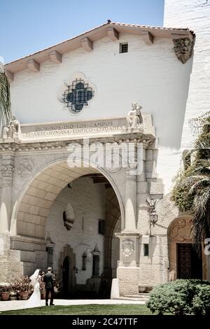 Beachten Sie die spanische Inschrift über dem Eingang des Santa Barbara County Courthouse durch den Säulenbogen am Eingangsweg von Braut und Bräutigam Stockfoto