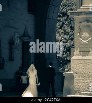 Rückansicht von Braut und Bräutigam, die in den Säulengang in Richtung Innenhof und versunkene Gärten des Santa Barbara County Courthouse, CA, gehen Stockfoto