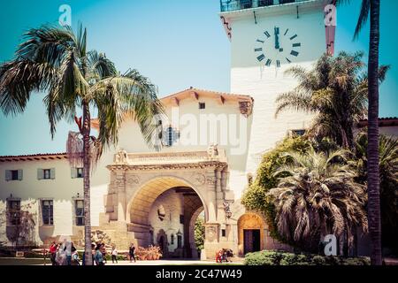 Menschen um das Wahrzeichen, Santa Barbara County Courthouse Eingang und Blick durch den Säulenbogen Eingang zu den Gärten in Santa Barbara, CA, Stockfoto