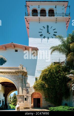 Ein Mann, der kurz vor dem Betreten des Uhrturms im Santa Barbara County Courthouse in der Nähe des Säulenbogens in den Gärten in Santa Barbara, CA, steht Stockfoto