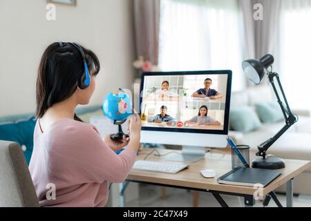 Asian Woman Teaching Geography per Videokonferenz E-Learning und fröhliche Grundschüler mit Blick auf Globe, Homeschooling und dist Stockfoto