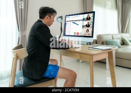 Gemischter Rennunternehmer trägt Formalwear Business Anzug auf der Oberseite und Boxer Hosen auf der Unterseite, zeigt andere Menschen auf dem Bildschirm in formalen fridays Geschäft ou Stockfoto