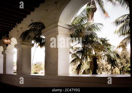 Blick von der Kolonnade im maurischen Stil mit Bögen und umgeben von Palmen mit Sonnenstrahlen in Santa Barbara, CA, USA Stockfoto