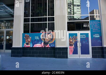 Black Lives Matter protestieren mit einem schwarzen Jungen, der nach den Protesten von George Floyd in der Innenstadt von Oakland die Hände auf einem begrateten Gebäude aufhält. Stockfoto