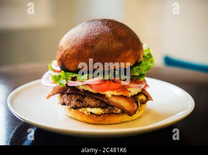 Speck-Burger mit Ei, Tomaten, Zwiebeln und Salat Stockfoto