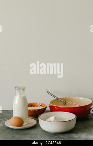 Vertikale Aufnahme von Zutaten auf einem grauen Tisch mit einem Weiße Wand auf dem Hintergrund Stockfoto